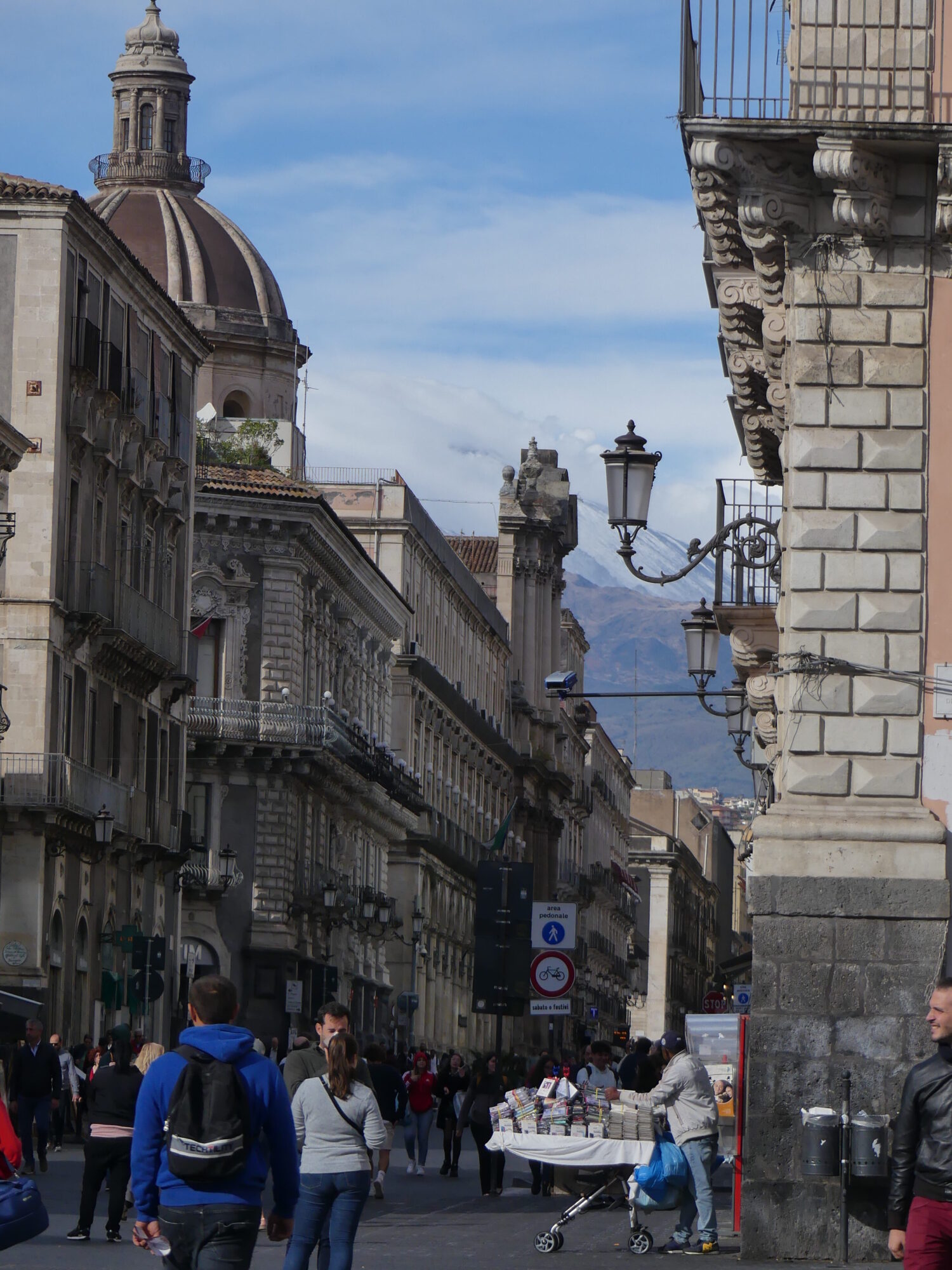 Baroque pedestrian street with Etna in the background above the roofs.